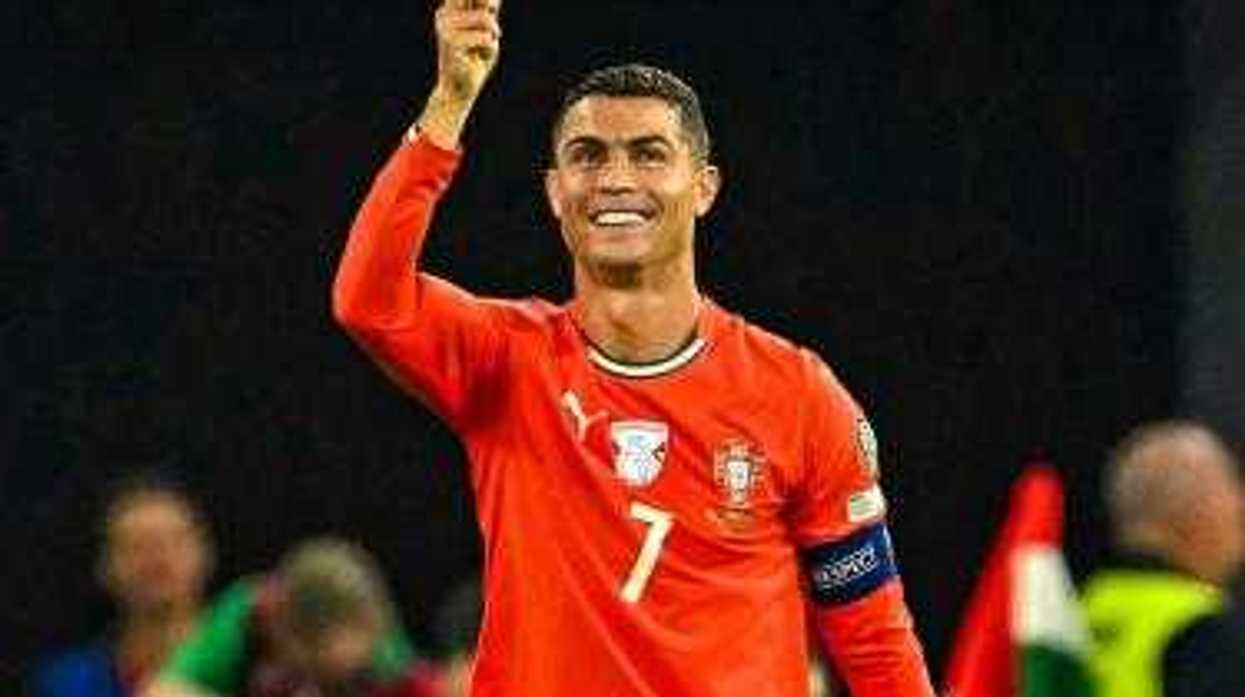 Jugador de la selección de Portugal con el número 7 y el brazalete de capitán señala hacia arriba y sonríe durante un partido.