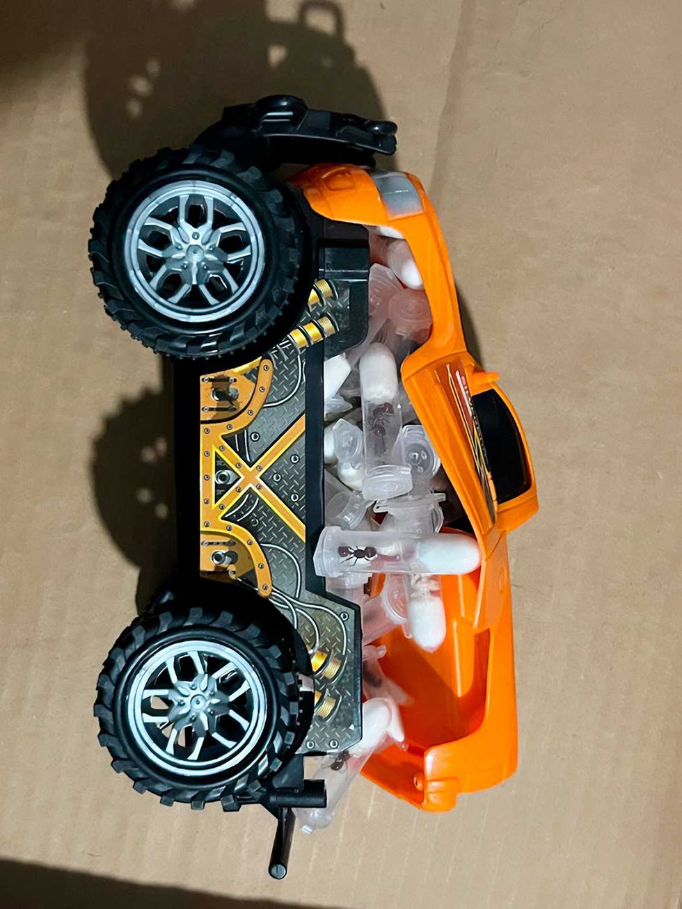 Juguete tipo camioneta anaranjada, abierto, con tubos de ensayo ocultos en su compartimento interior.