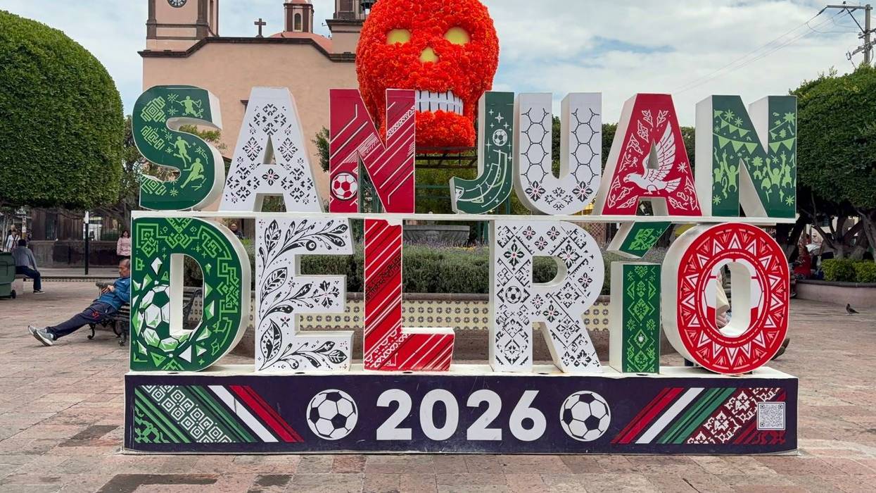 Letras monumentales de San Juan del Río 2026 en una plaza del centro, con la calavera de flores naranjas y un templo al fondo