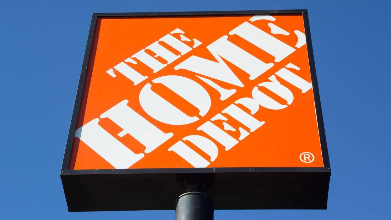 Letrero naranja con el logotipo de The Home Depot, visto desde abajo contra un cielo azul.