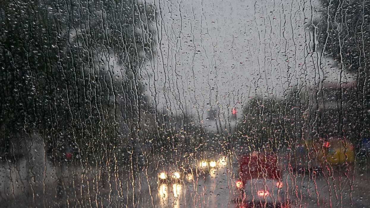 Lluvia sobre un cristal y autos con luces encendidas al fondo, en el contexto del pronóstico de lluvias en Querétaro
