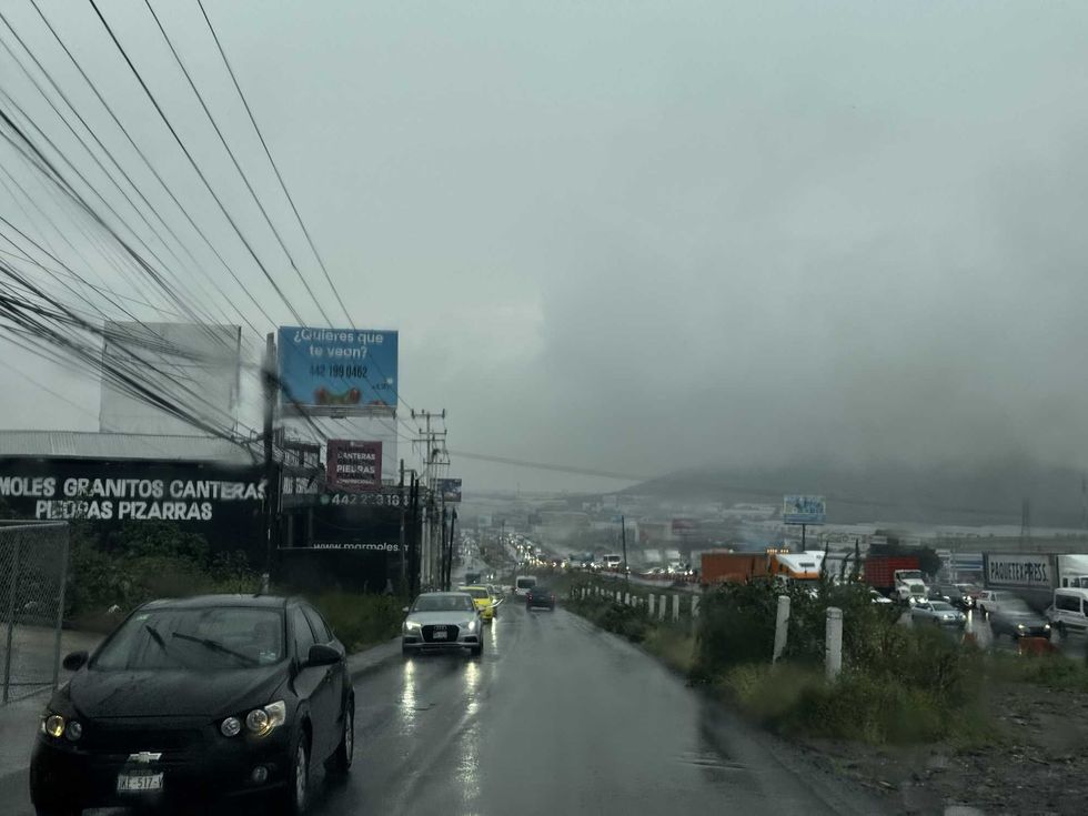 Lluvia sobre una vialidad con tr\u00e1fico y cielo cubierto en Quer\u00e9taro, con lluvias en aumento seg\u00fan el SMN.