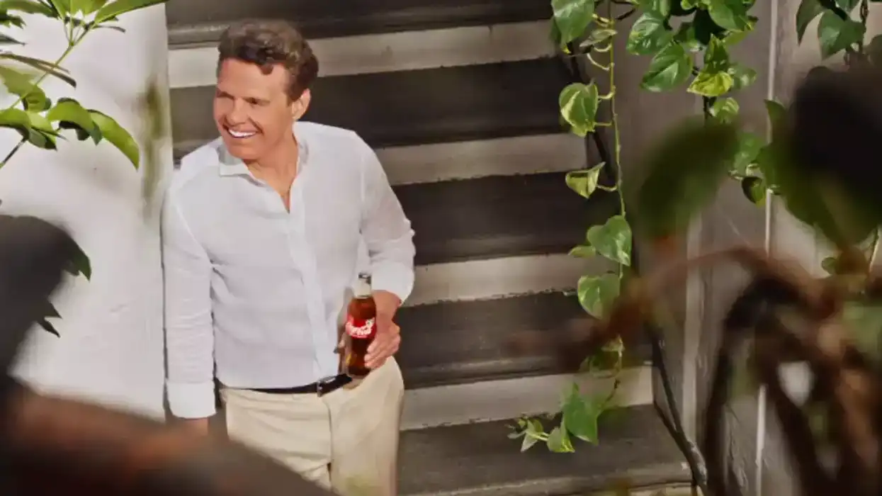 Luis Miguel baja unas escaleras sosteniendo una botella de Coca-Cola durante la grabación de la campaña por el centenario de la marca en México