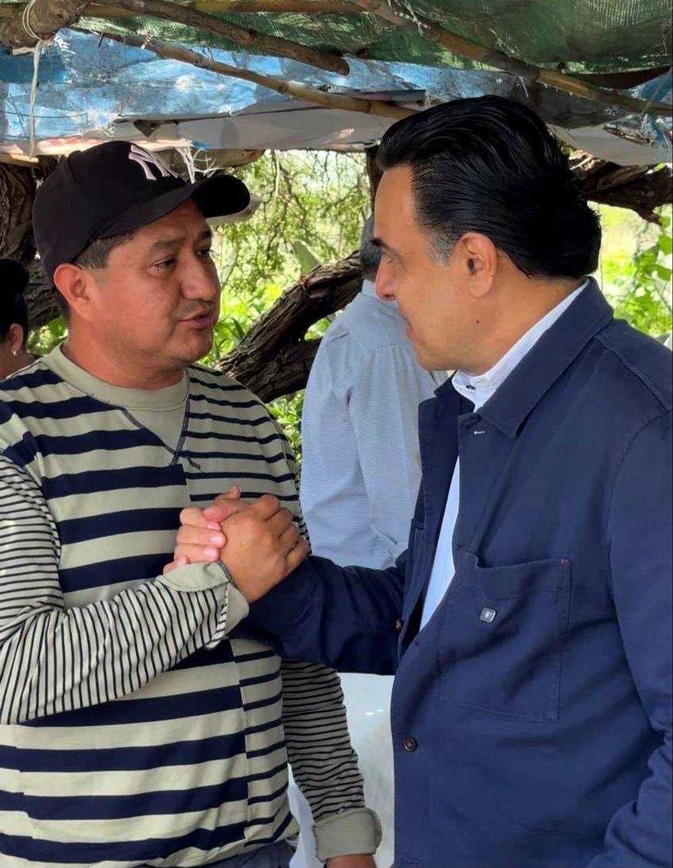 Luis Nava saluda de mano a un asistente con gorra durante la reuni\u00f3n en Pedro Escobedo