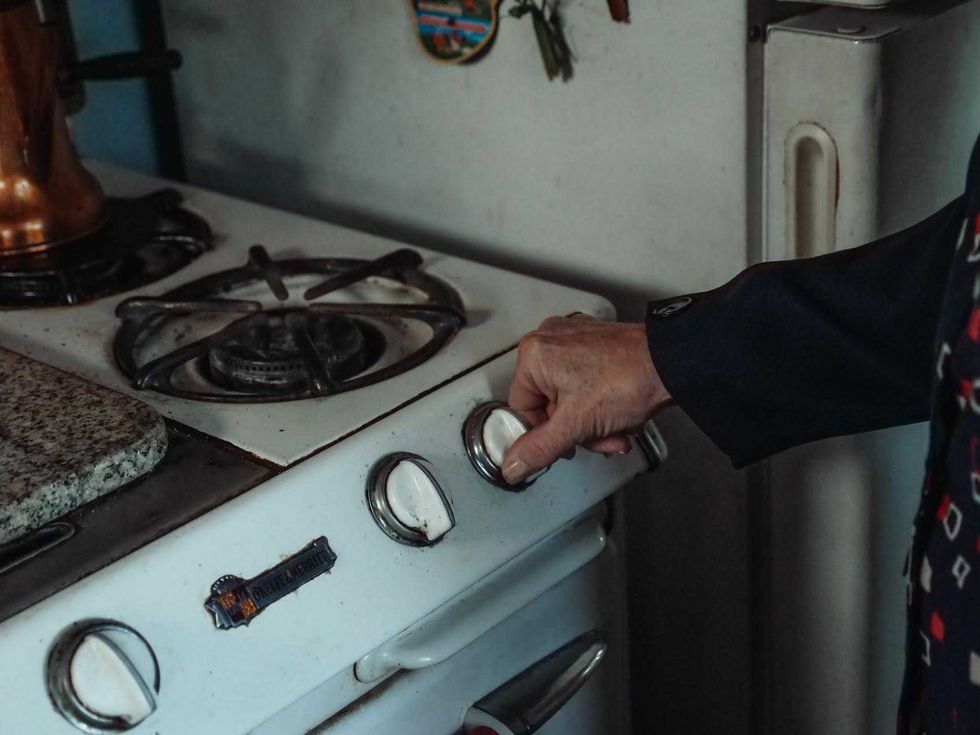 Mano ajusta la perilla de una estufa de gas en una cocina