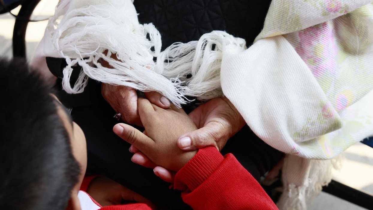 Manos de adulto mayor y niño entrelazadas durante programa de pláticas del DIF Querétaro sobre convivencia intergeneracional