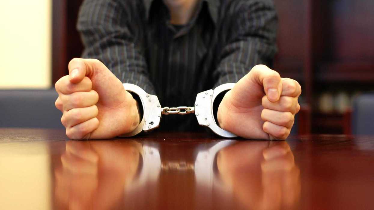 Manos esposadas sobre una mesa, imagen genérica alusiva a un proceso penal por violación equiparada.