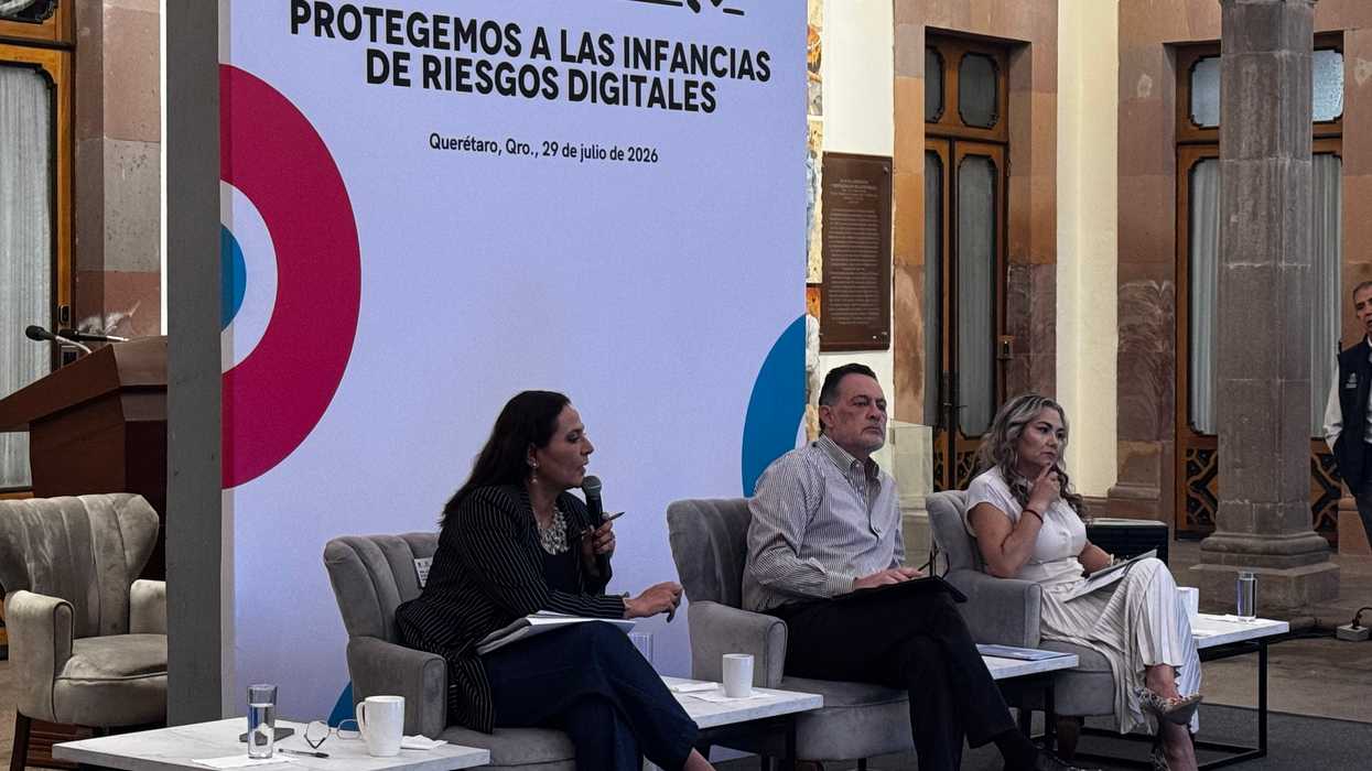 Martha Elena Soto Obregón, secretaria de Educación de Querétaro, habla al micrófono durante un panel sentada junto a otras dos personas, con telón de fondo "Aquí Contigo: Protegemos a las infancias de riesgos digitales", Querétaro, 29 de julio de 2026.