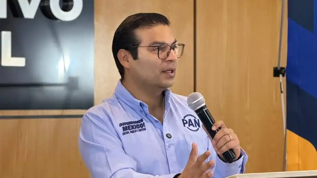 Martín Arango, dirigente estatal del PAN en Querétaro, sostiene un micrófono durante una conferencia de prensa en la sede partidista.