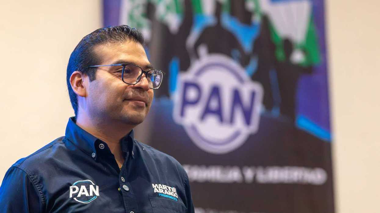 Martín Arango García, presidente del PAN en Querétaro, con camisa azul marino con el logotipo del partido frente a una lona del PAN