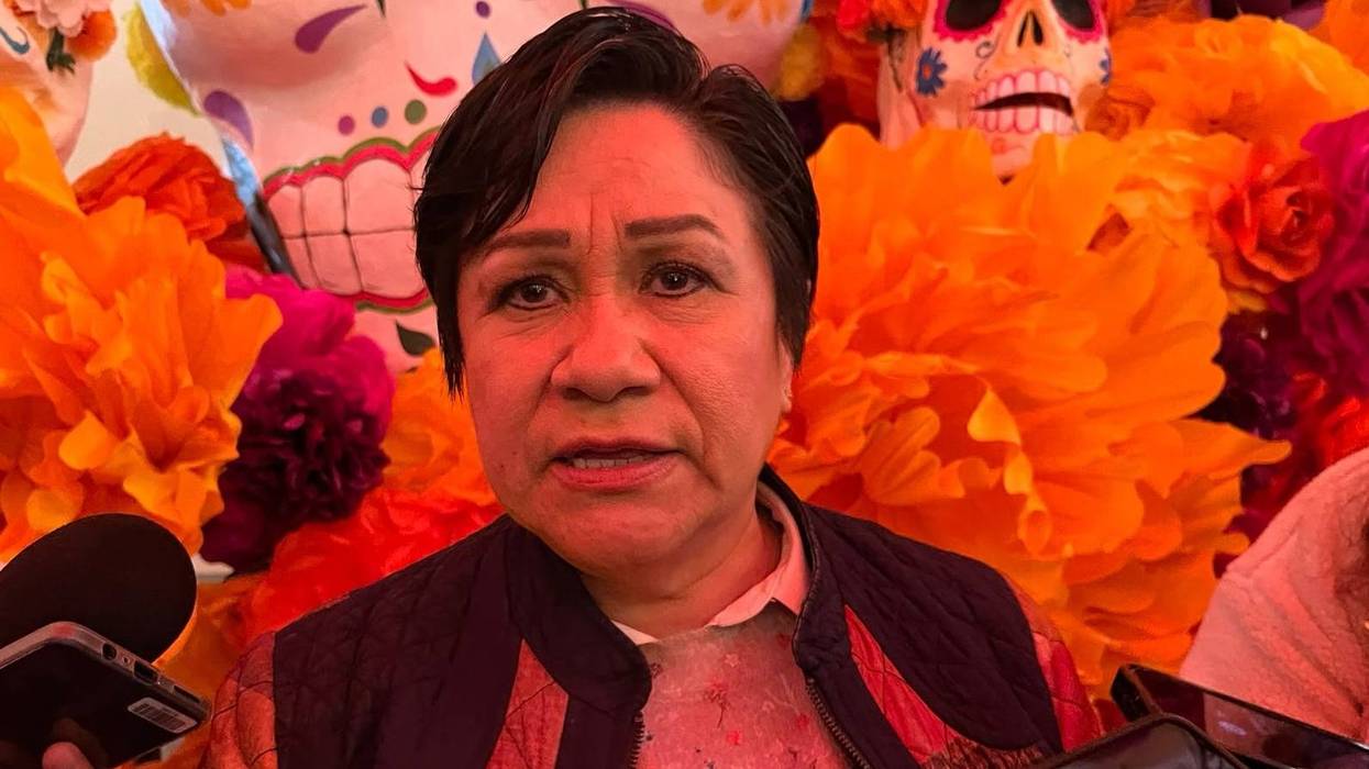 Martina Pérez Rendón, secretaria de Salud estatal, habla ante micrófonos frente a flores de cempasúchil y calaveras