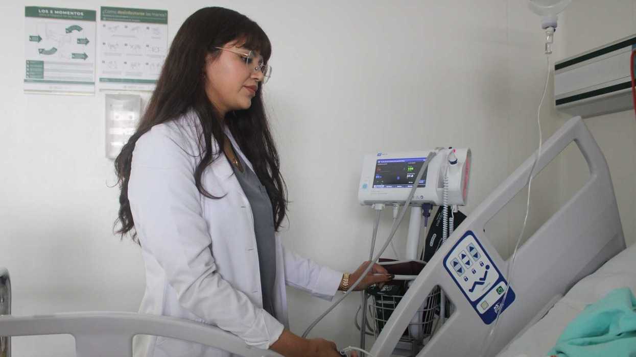 Médica con bata blanca junto a un monitor de signos vitales y un paciente; rehabilitación cardiaca y disautonomía