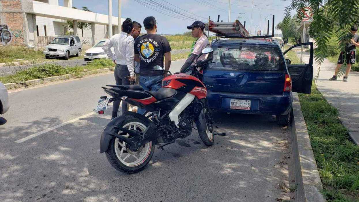 Motociclista impacta por alcance contra vehículo Chevrolet azul detenido irregularmente en vialidad continua de avenida Universidad en San Juan del Río.