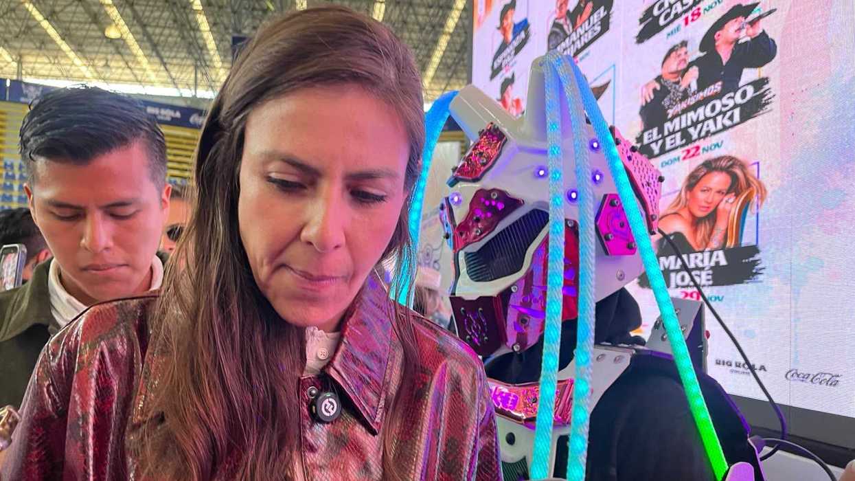 Mujer con chamarra roja de textura reptil frente a un teléfono que graba audio, durante la entrevista sobre la reapertura de Cuatro Palos, Pinal de Amoles.