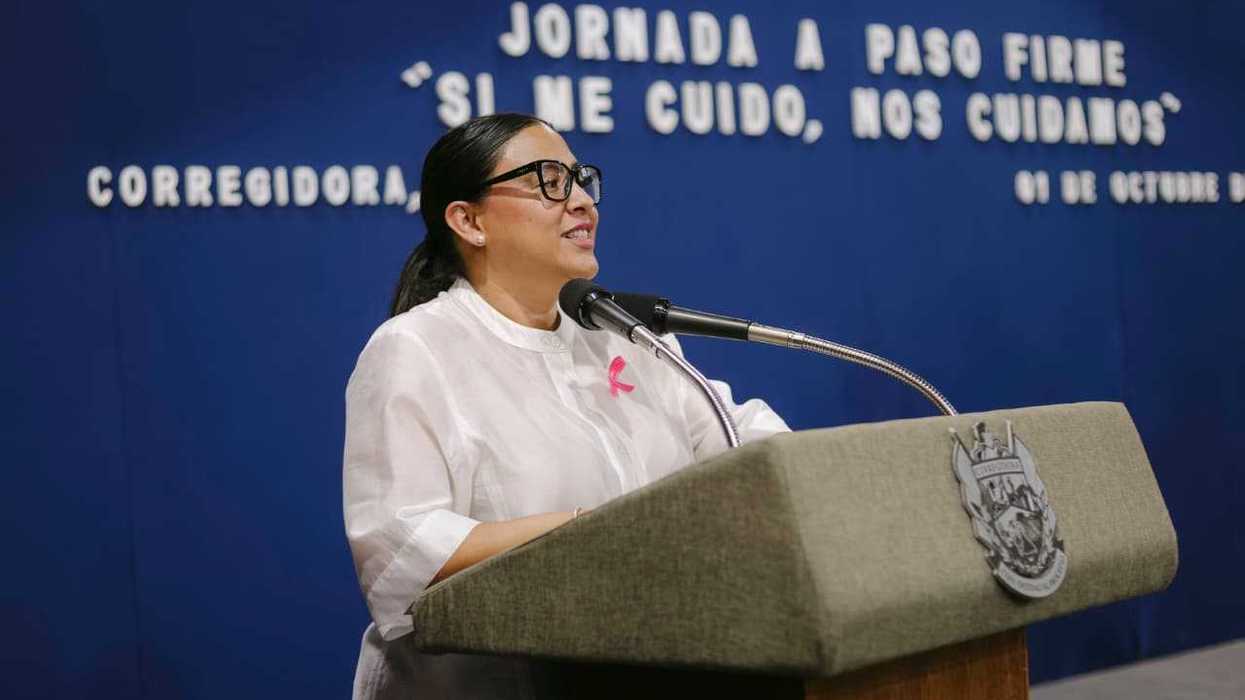 Mujer con micrófono se dirige a trabajadoras sentadas en la jornada A Paso Firme sobre cáncer de mama en Corregidora.