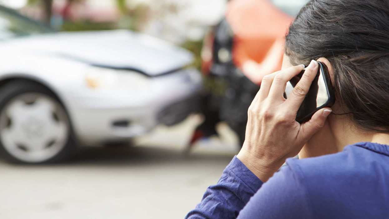 Mujer consulta su teléfono junto a dos vehículos con daños leves tras un percance vial