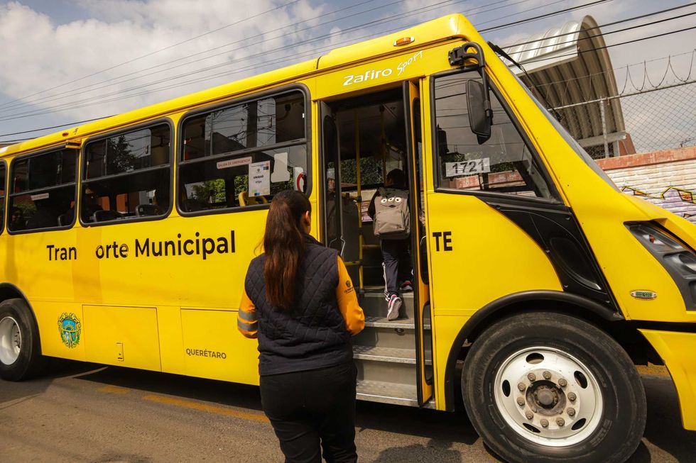 Mujer observa a pasajero abordar autob\u00fas amarillo de Transporte Municipal de Quer\u00e9taro en delegaci\u00f3n, 2026.