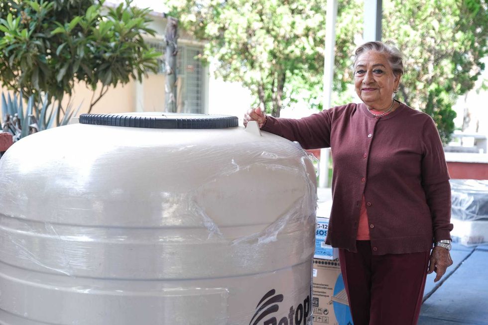 Mujer posa junto a un tinaco entregado por el Programa de Coinversi\u00f3n Social en San Rafael, Corregidora