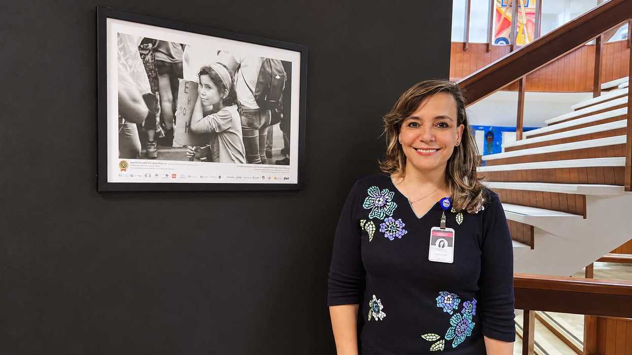 Mujer sonriente junto a fotografía enmarcada y escalera de madera, imagen de apoyo de la elección de rectoría de la UAQ