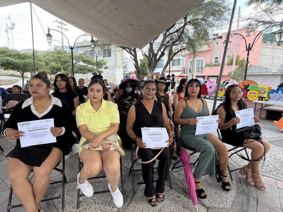 Mujeres muestran sus reconocimientos durante la clausura de cursos de autoempleo en Col\u00f3n; al fondo se observan pi\u00f1atas elaboradas por las participantes.