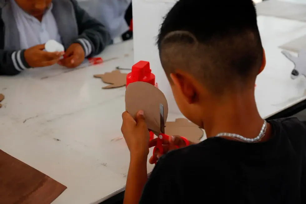 Ni\u00f1a o ni\u00f1o participante muestra una manualidad elaborada durante el curso de verano en Col\u00f3n, con rostro difuminado por la fuente