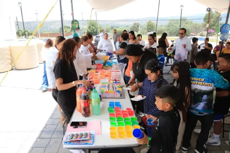 Ni\u00f1as y ni\u00f1os se acercan a una mesa con materiales durante una actividad recreativa del curso de verano en Col\u00f3n, Quer\u00e9taro