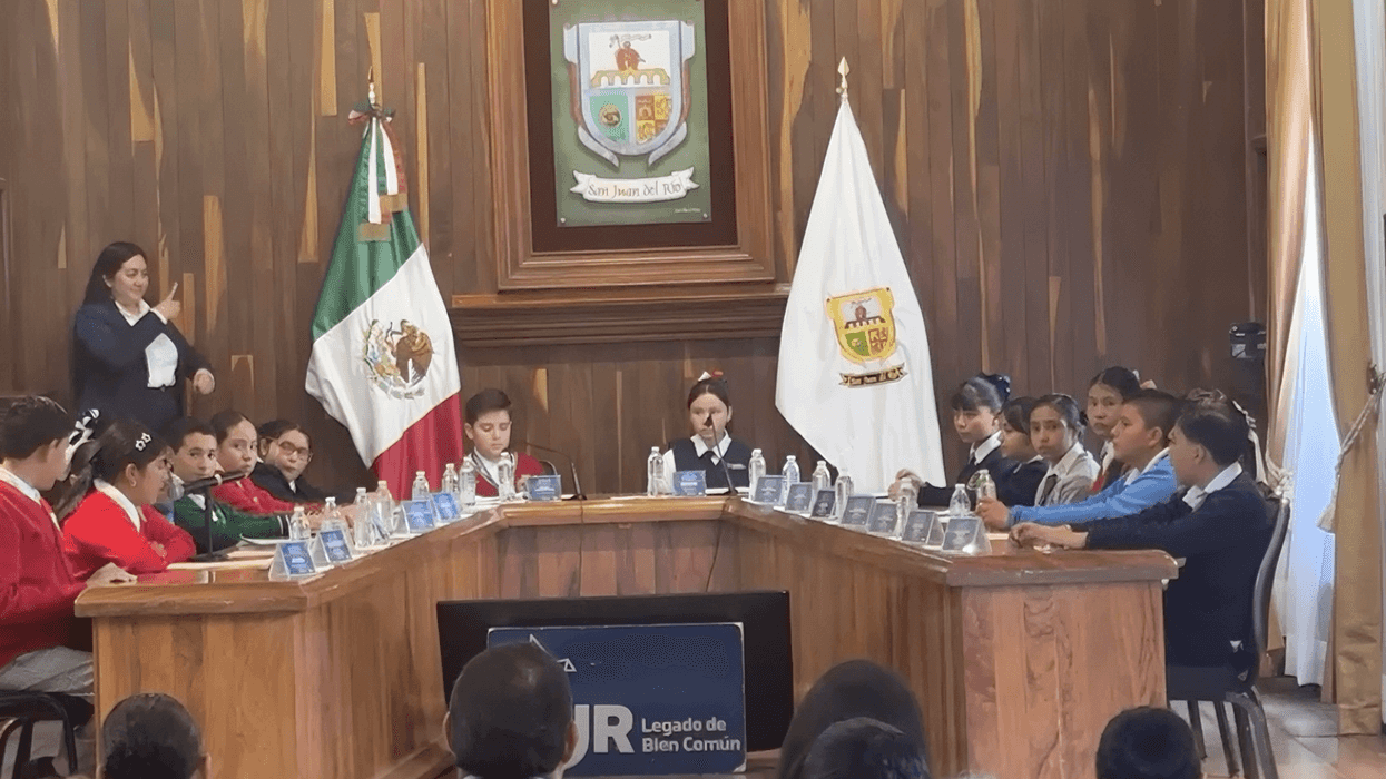Niñas y niños sentados en los lugares de regidores durante la sesión de cabildo infantil en San Juan del Río.