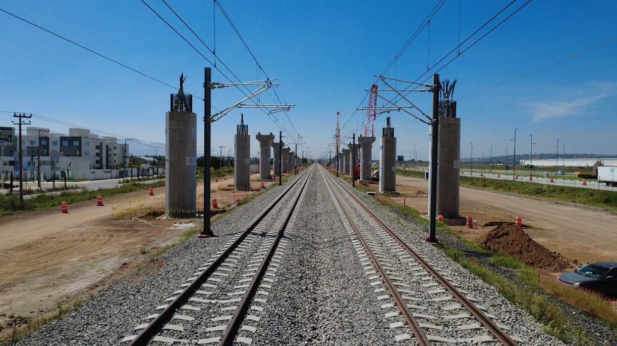 Obras de construcción del tren de pasajeros México-Querétaro en avenida Corregidora Norte con maquinaria pesada y señalización vial en la capital queretana