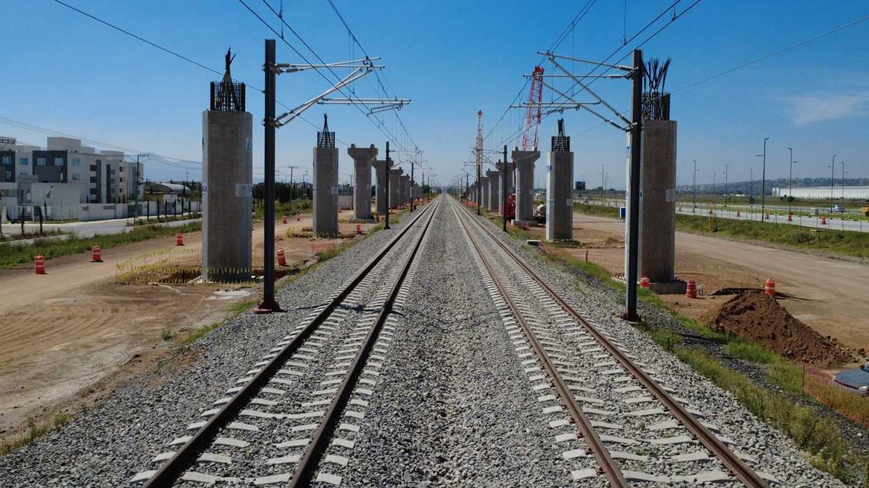 Obras de construcción del tren de pasajeros México-Querétaro en avenida Corregidora Norte con maquinaria pesada y señalización vial en la capital queretana