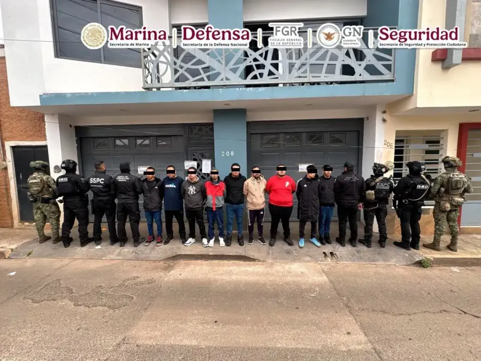 Ocho presuntos integrantes del CJNG detenidos frente a inmueble urbano custodiados por elementos de corporaciones federales.