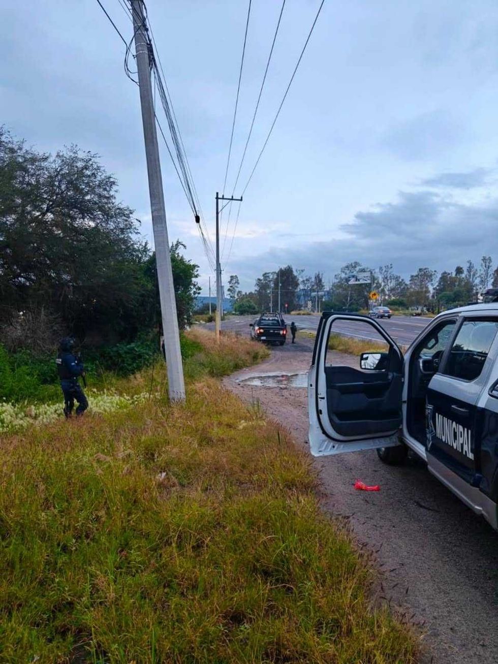 Oficial de la Polic\u00eda Municipal resguarda la orilla de una carretera durante un operativo, con patrulla estacionada