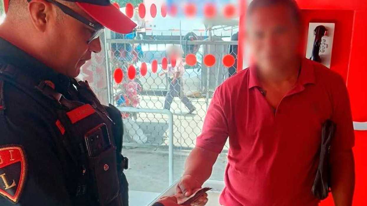 Oficial de la Policía Bancaria e Industrial entrega dinero en efectivo a un hombre dentro de una sucursal bancaria en la Ciudad de México.