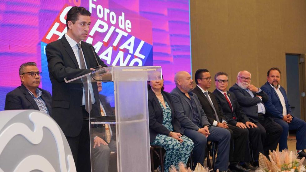Orador se dirige al p\u00fablico desde el podio del Foro de Capital Humano CANACINTRA, con el cartel de reconocimiento al fondo.