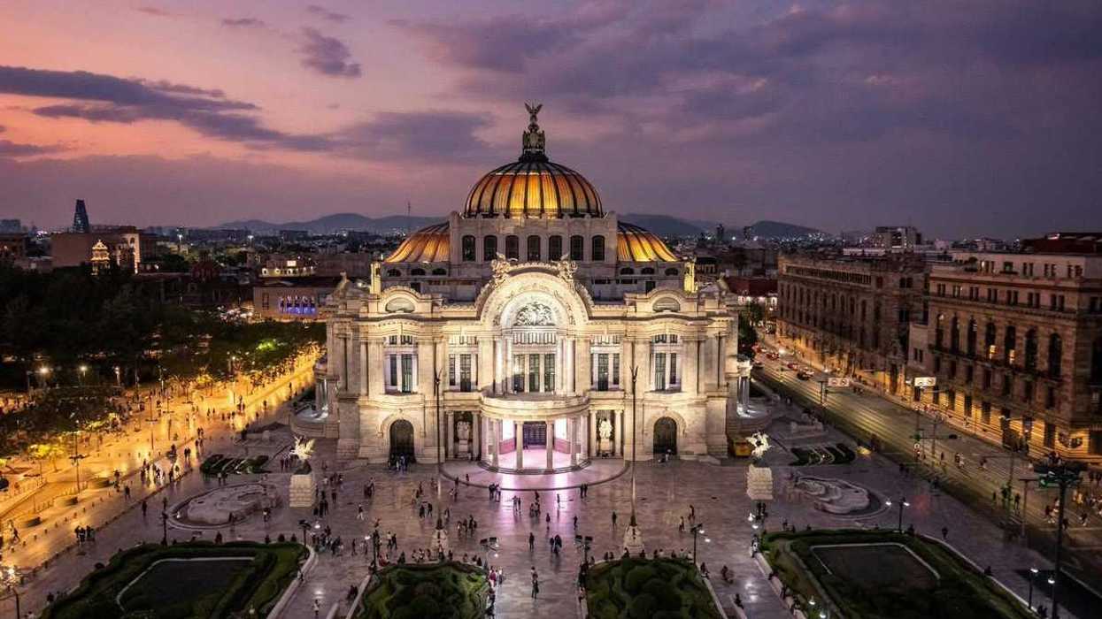 Palacio de Bellas Artes iluminado al atardecer, con su cúpula y la plaza frontal, en el Día Mundial de la Arquitectura