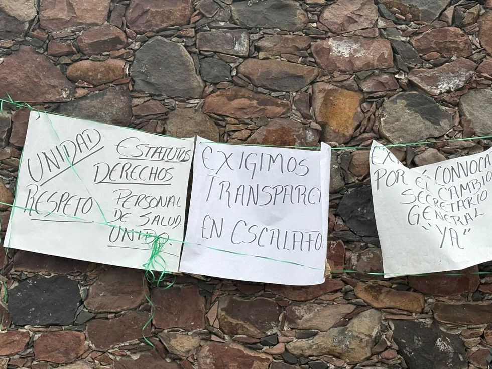 Pancartas en muro de piedra piden transparencia en el escalaf\u00f3n y cambio de secretario general del sindicato de salud
