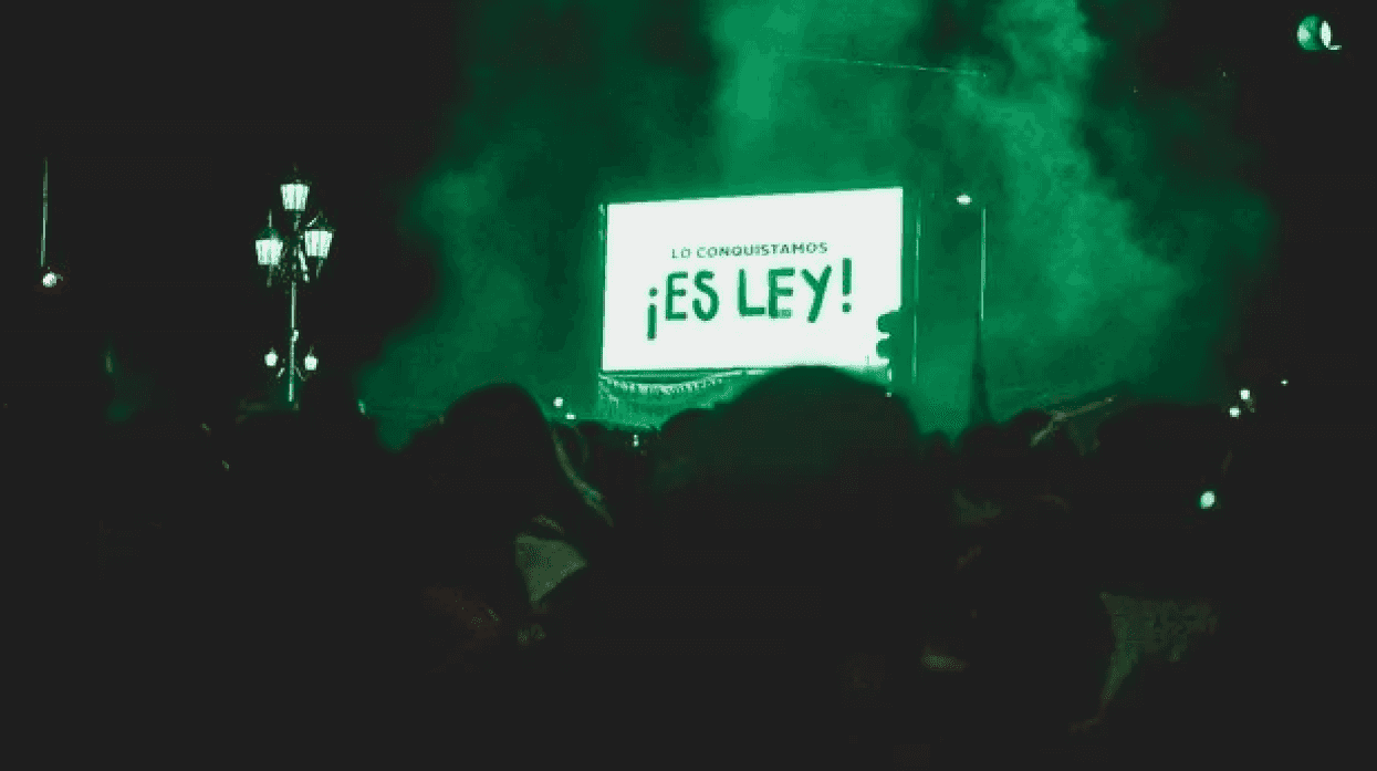 Pantalla con la leyenda «Lo conquistamos ¡Es ley!» entre humo verde frente a una multitud, en una concentración por el aborto legal en Argentina