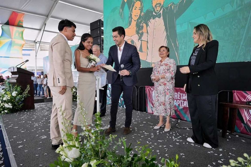 Pareja de novios recibe documento de manos del presidente municipal Felifer Mac\u00edas en el pres\u00eddium de la ceremonia colectiva.