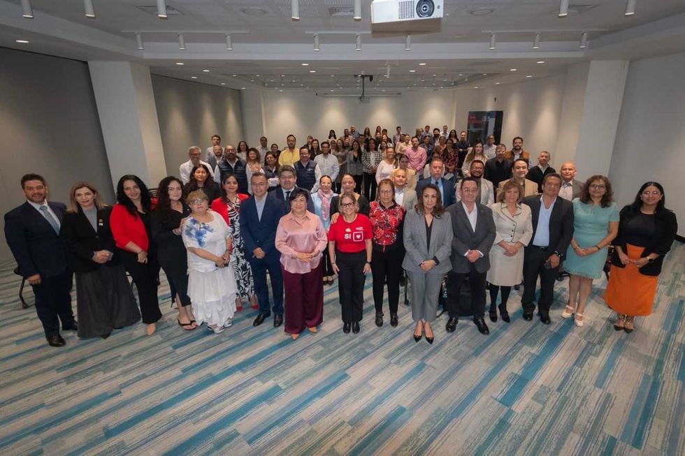 Participantes en la ceremonia de adhesi\u00f3n de Quer\u00e9taro a la estrategia HEARTS posan para una fotograf\u00eda grupal en sal\u00f3n de conferencias
