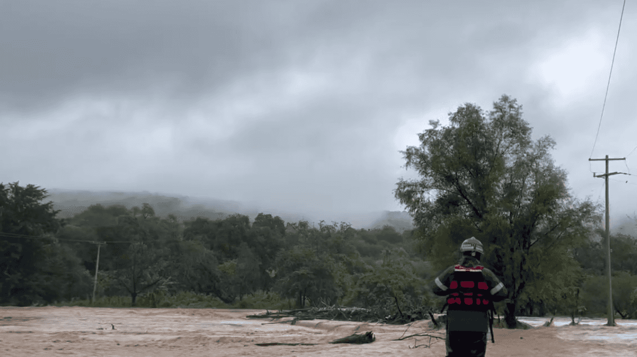 Persona con casco y chaleco salvavidas frente a una corriente lodosa durante las lluvias en la sierra de Querétaro