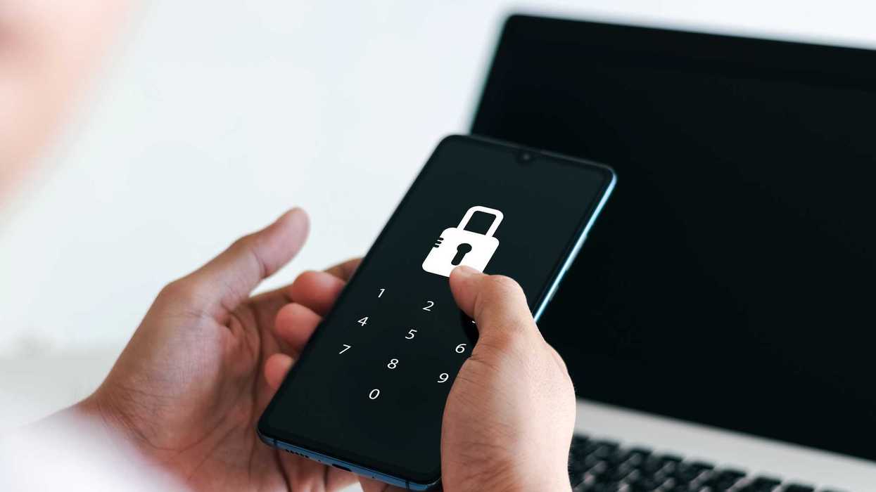 Persona sostiene un teléfono con pantalla de candado y teclado numérico frente a una laptop, ilustrando recomendaciones de seguridad financiera digital.
