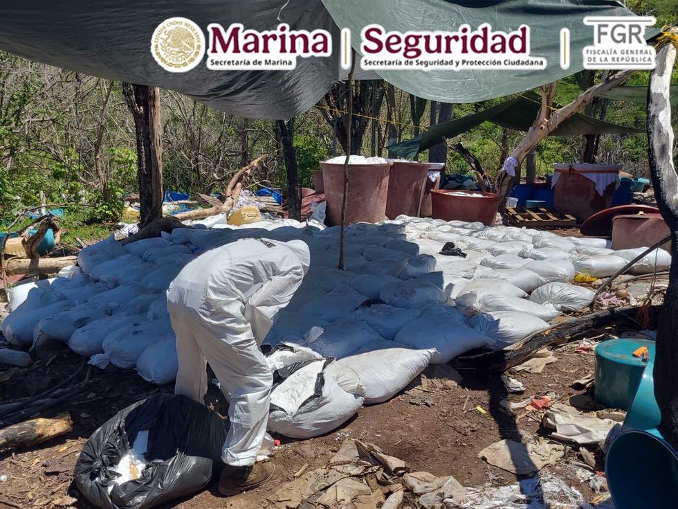 Personal con traje de bioseguridad revisa costales del laboratorio clandestino de metanfetamina en Sinaloa