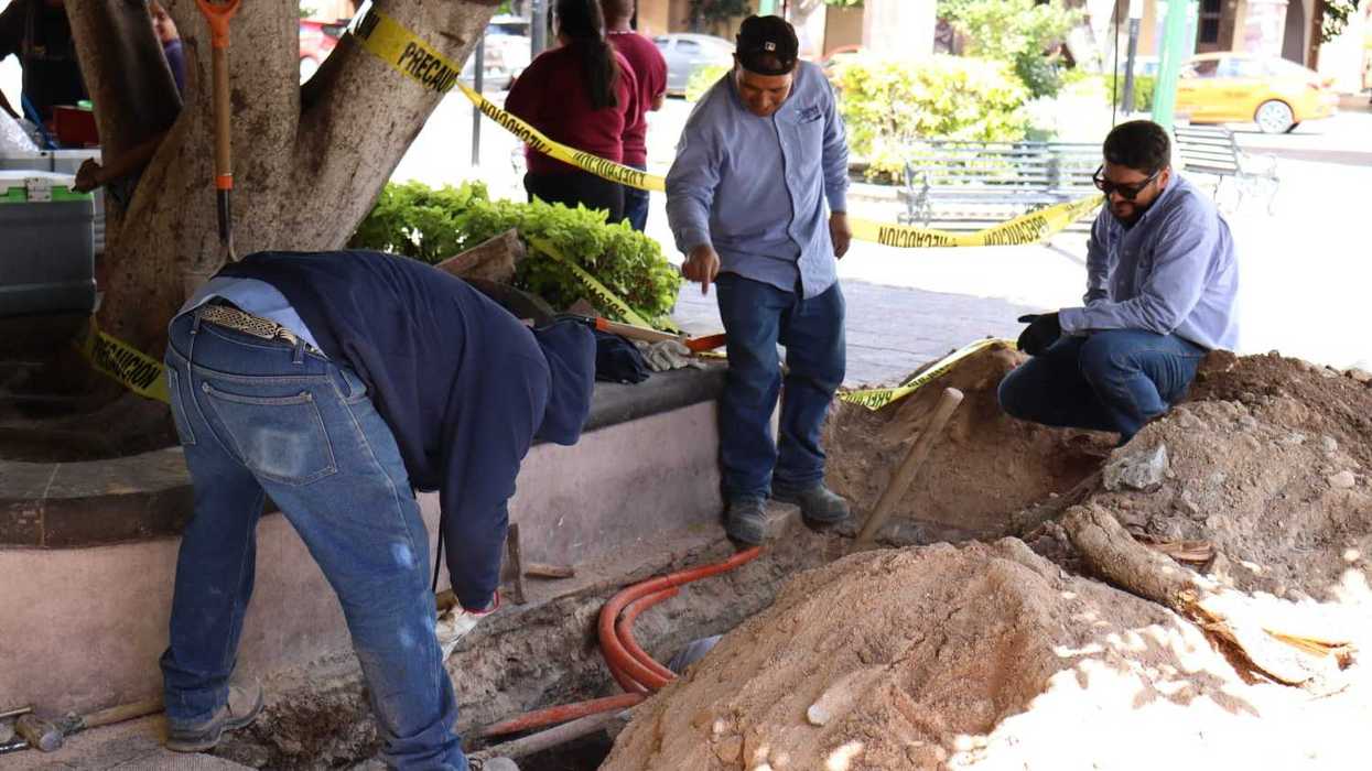 Personal de la JAPAM trabaja en una zanja para reparar la tubería en el Jardín de la Familia de San Juan del Río