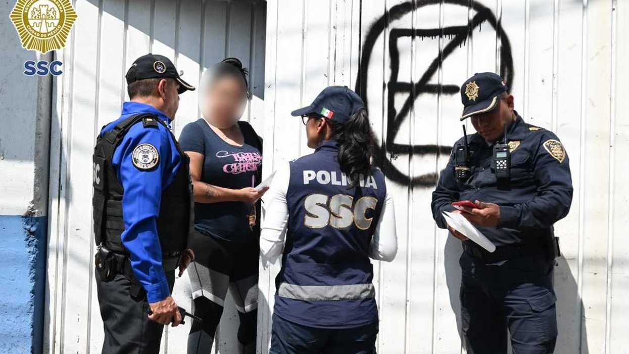 Personal de la SSC y de Protección Civil muestra un documento a un hombre de rostro difuminado en la entrada de un inmueble