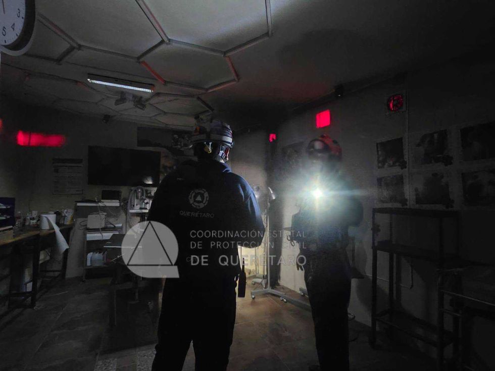 Personal de Protecci\u00f3n Civil con casco y equipo de iluminaci\u00f3n realiza labores de inspecci\u00f3n dentro del establecimiento comercial afectado por el conato de incendio.