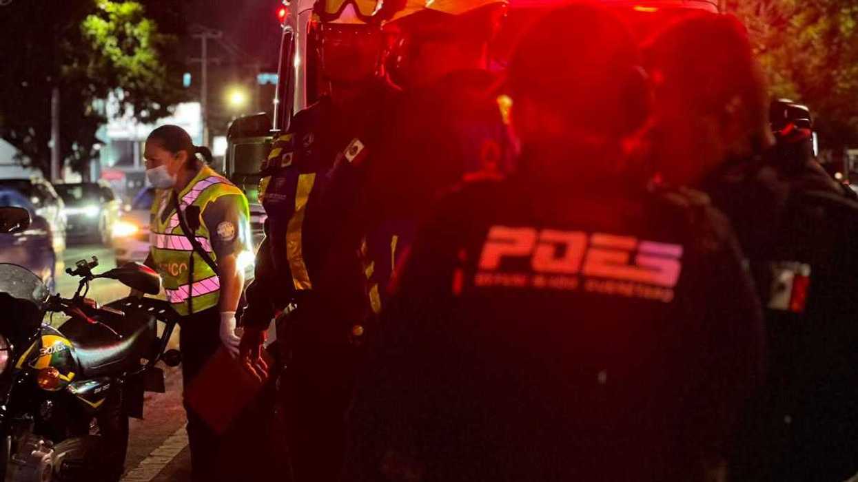 Personal de Protección Civil de espaldas frente a una ambulancia con luces encendidas durante la atención de un accidente vial en Querétaro.