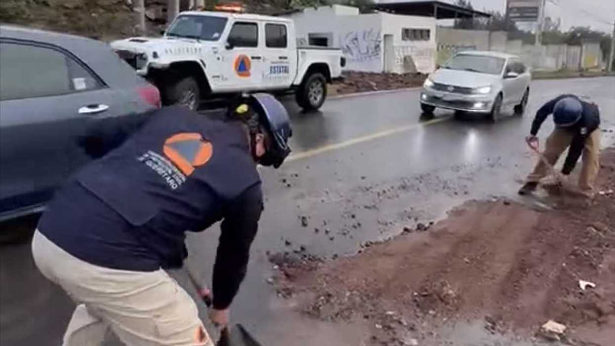 Personal de Protección Civil Querétaro retira con palas el material de arrastre sobre la carpeta asfáltica de Cuesta China Vieja.