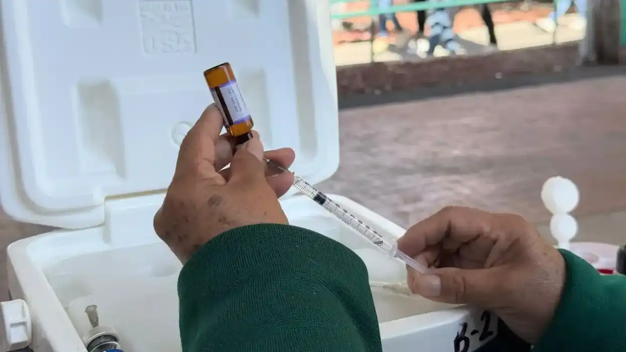 Personal de salud aplica una vacuna en el brazo de una mujer.