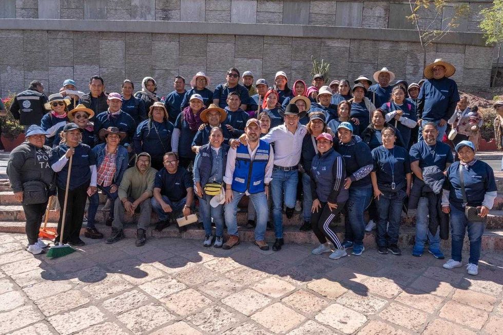 Personal de servicios p\u00fablicos municipales con uniforme beige y chalecos azules posa frente a camiones en El Marqu\u00e9s.