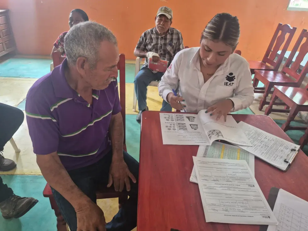 Personal educativo asesora a habitantes rurales durante el llenado de documentos