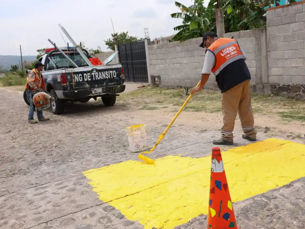 Personal municipal aplica pintura amarilla sobre un reductor de velocidad.